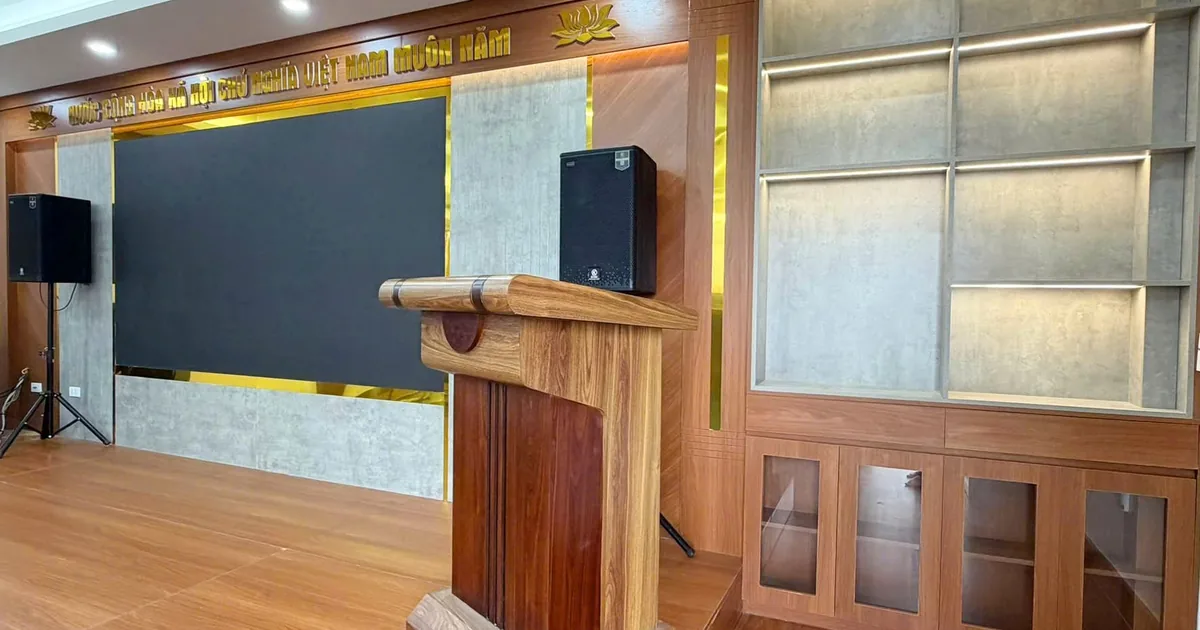 Bục phát biểu gỗ tự nhiên đặt trên sân khấu hội trường, chụp nghiêng thấy rõ thân bục