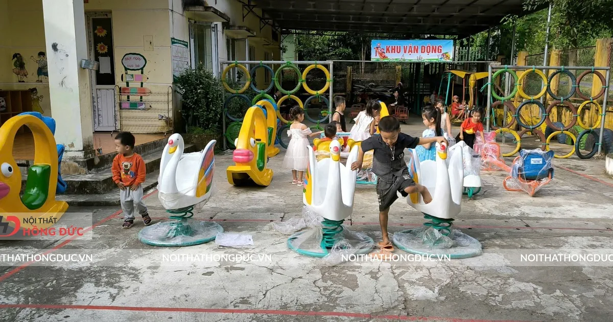 Dãy con nhún và tượng trang trí trên sân trường mầm non, có trẻ đang chơi
