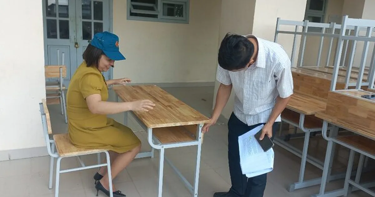 Hai người đang đo kiểm bàn ghế học sinh khi nhận hàng tại trường