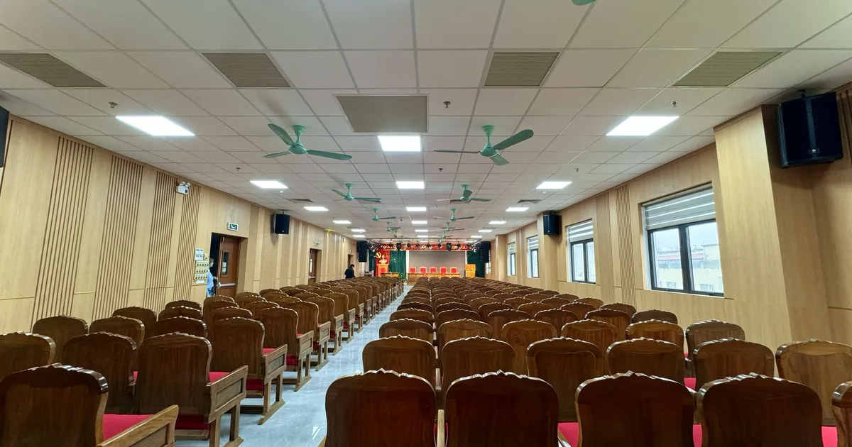 Hội trường đã lắp đủ ghế, chụp từ cuối phòng thấy toàn bộ dãy ghế và sân khấu