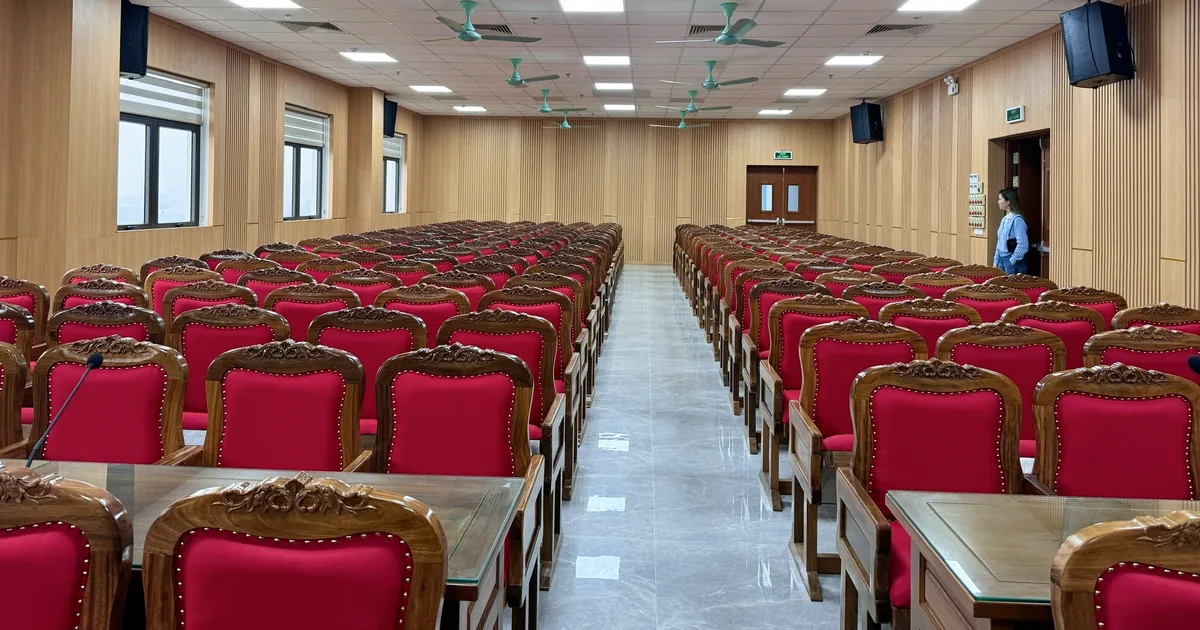 Hội trường đã lắp ghế khung gỗ bọc nỉ đỏ, chụp dọc theo lối đi giữa hai dãy