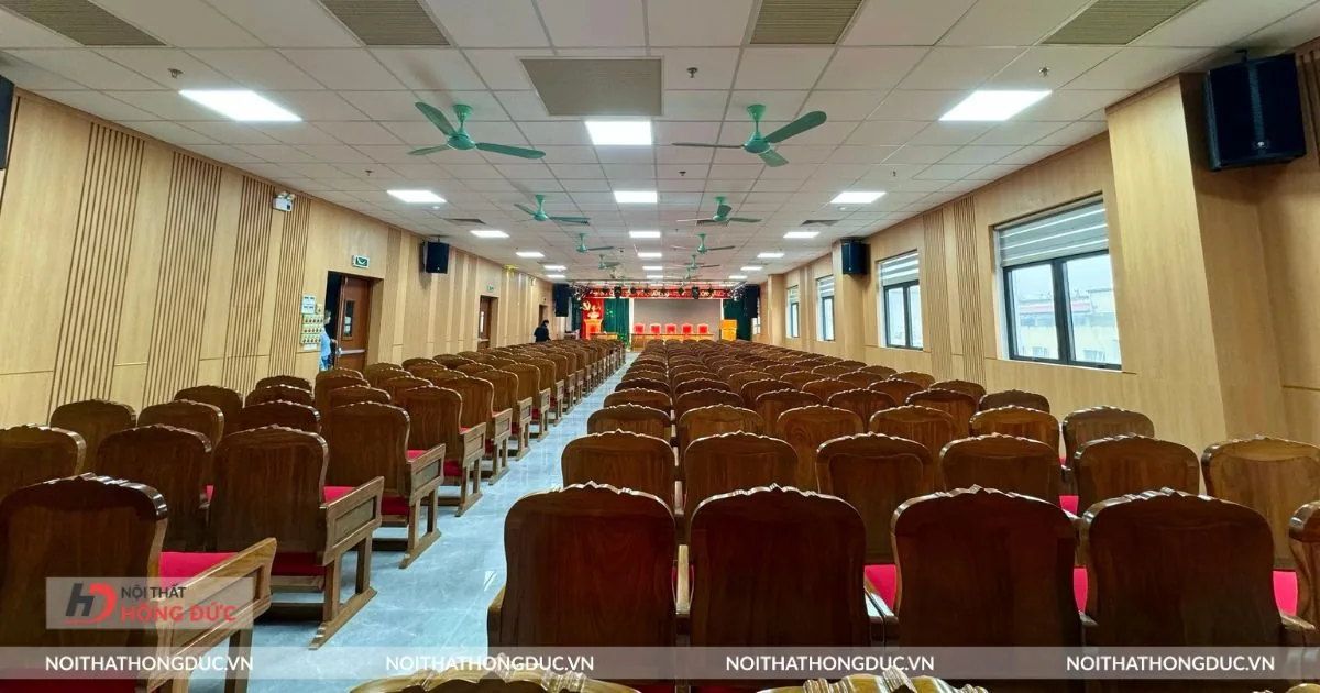 Hội trường đã lắp ghế, nhìn từ cuối phòng dọc theo lối đi giữa hai dãy ghế
