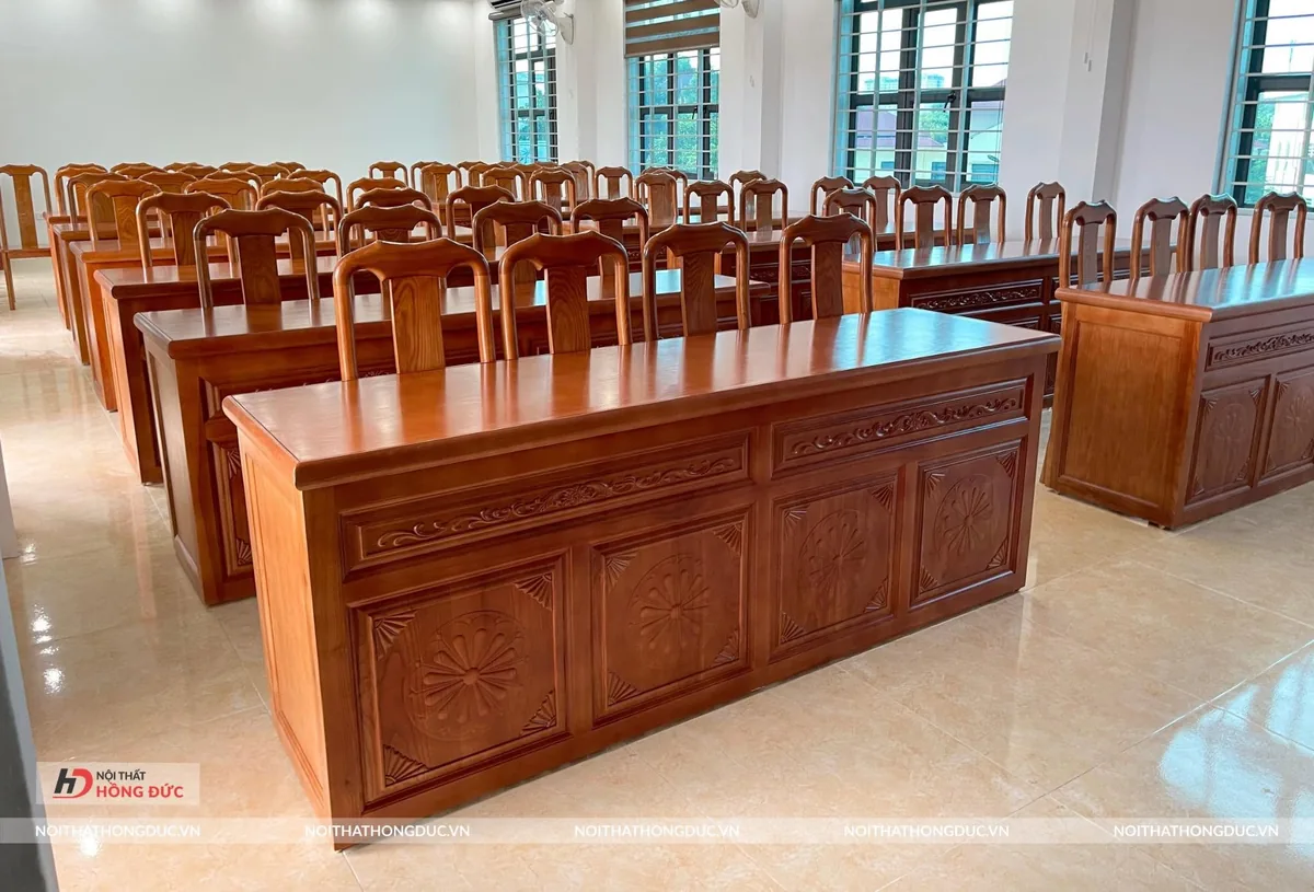 Hội trường nhỏ kê các dãy bàn gỗ và ghế tựa cho người dự họp