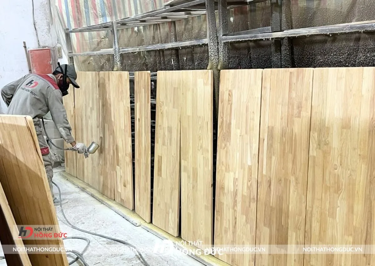 Mặt bàn gỗ ghép thanh đang được phun sơn hoàn thiện tại xưởng