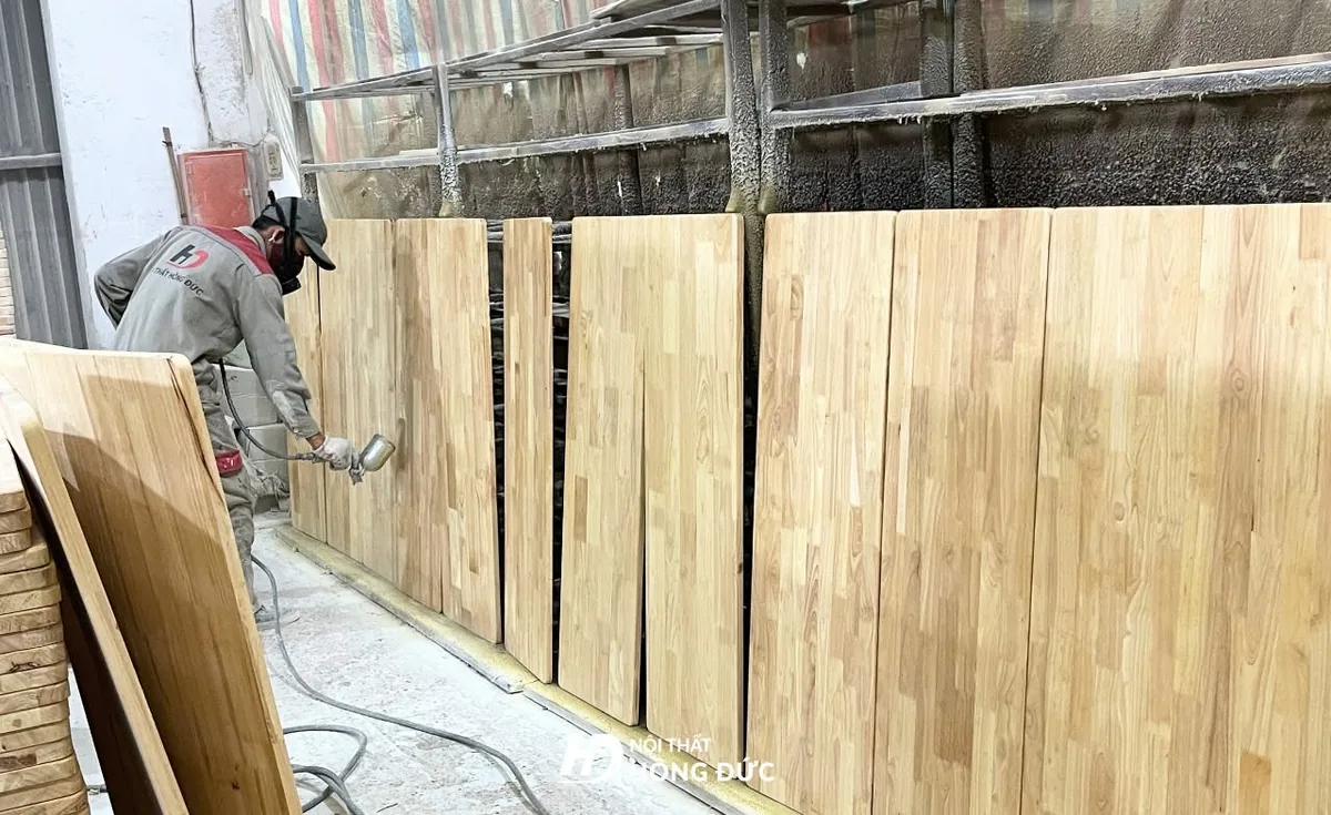 Mặt gỗ ghép thanh đang được phun lớp sơn phủ hoàn thiện